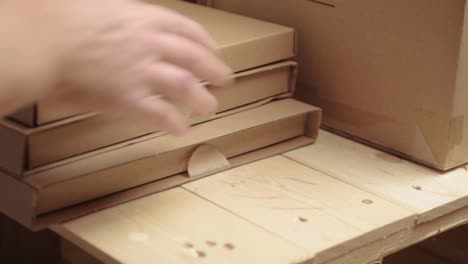 hand moving cardboard boxes on a wooden pallet