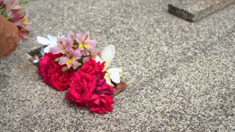 close up of hands leaving flowers on a granite grave