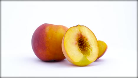 one whole and two parts of ripe peach fruit. rotating on the turntable isolated on the white background. close up. macro.