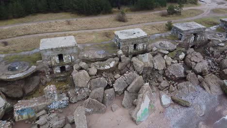 aerial view of abandoned seaside fortification building at karosta northern forts on the beach of baltic sea in liepaja in overcast spring day, pine wood, wide revealing drone shot moving backwards