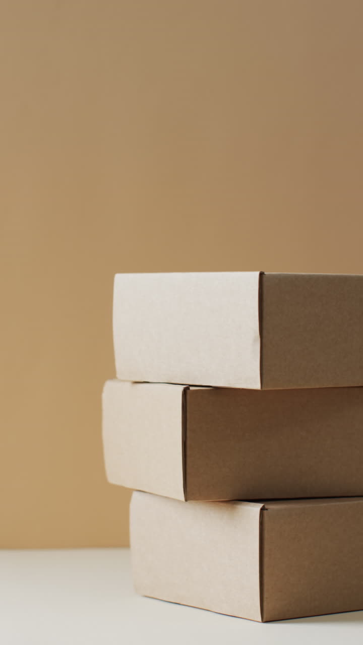 Vertical video of stacked cardboard boxes with copy space over brown background