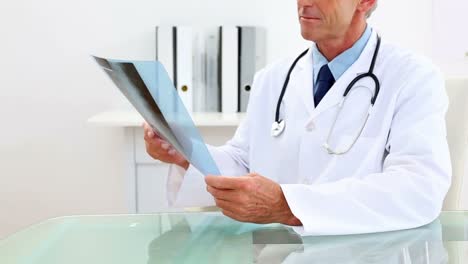 Mature-doctor-studying-at-xray-at-his-desk