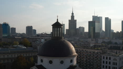 Fliegen-Sie-Um-Die-Kuppel-Der-Kirche-Der-Heiligen-Dreifaltigkeit-Mit-Dem-Goldenen-Kreuz-An-Der-Spitze.-Stadtbild-Mit-Hochhäusern-Im-Hintergrund.-Warschau,-Polen