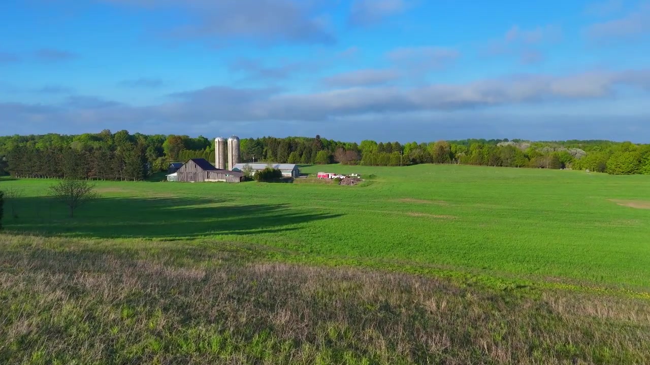 Landbrug med lade og siloer på grøn mark i Leelanau County, Michigan, set fra luften.