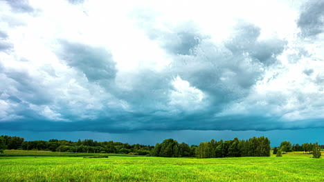 a thick pack of white clouds floats past over a green landscape