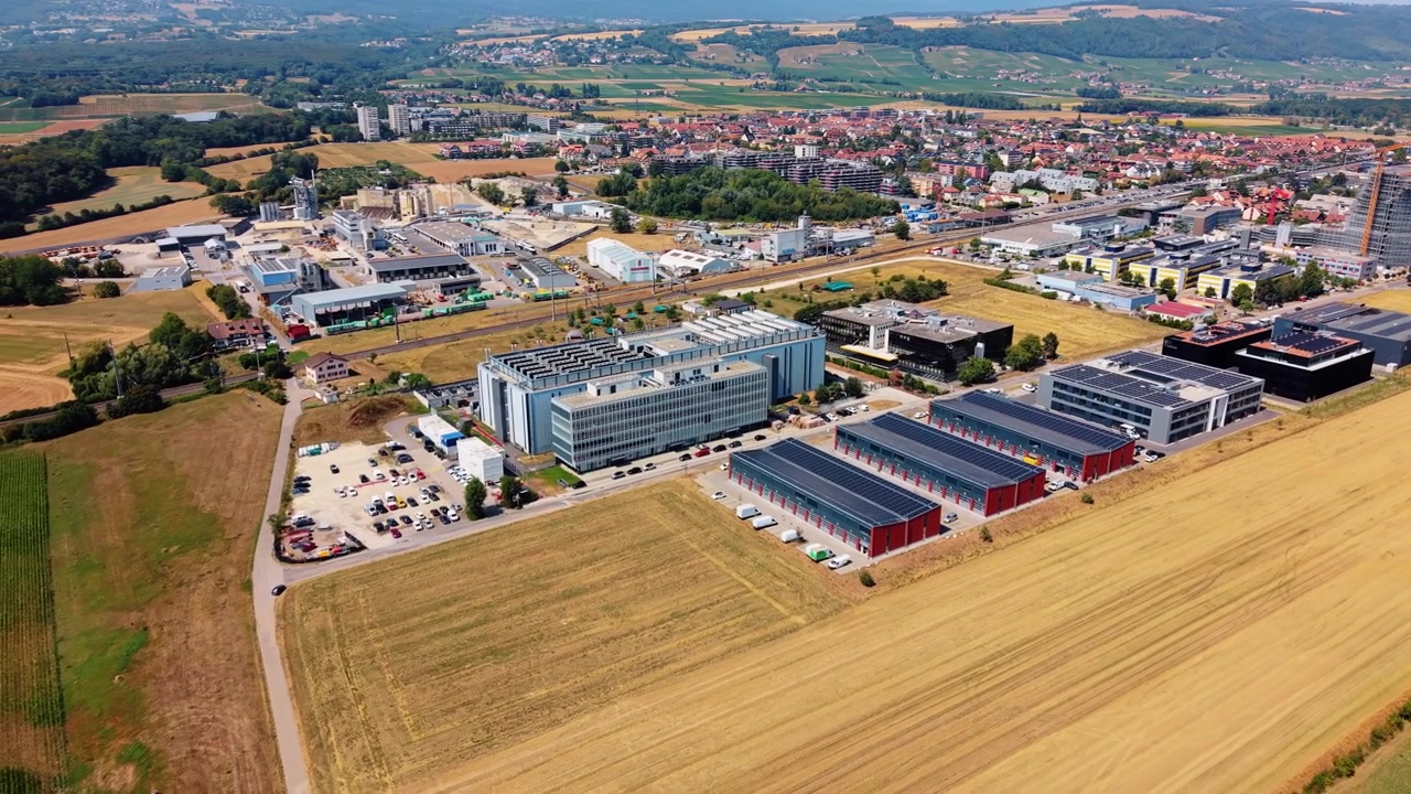 Il drone si allontana sopra un campo di grano rivelando un complesso di data center in lontananza