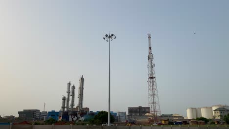 skyline of industrial area showing oil reservoirs, telecom pole, smoke stacks, lights, oil refinery chimney and factories