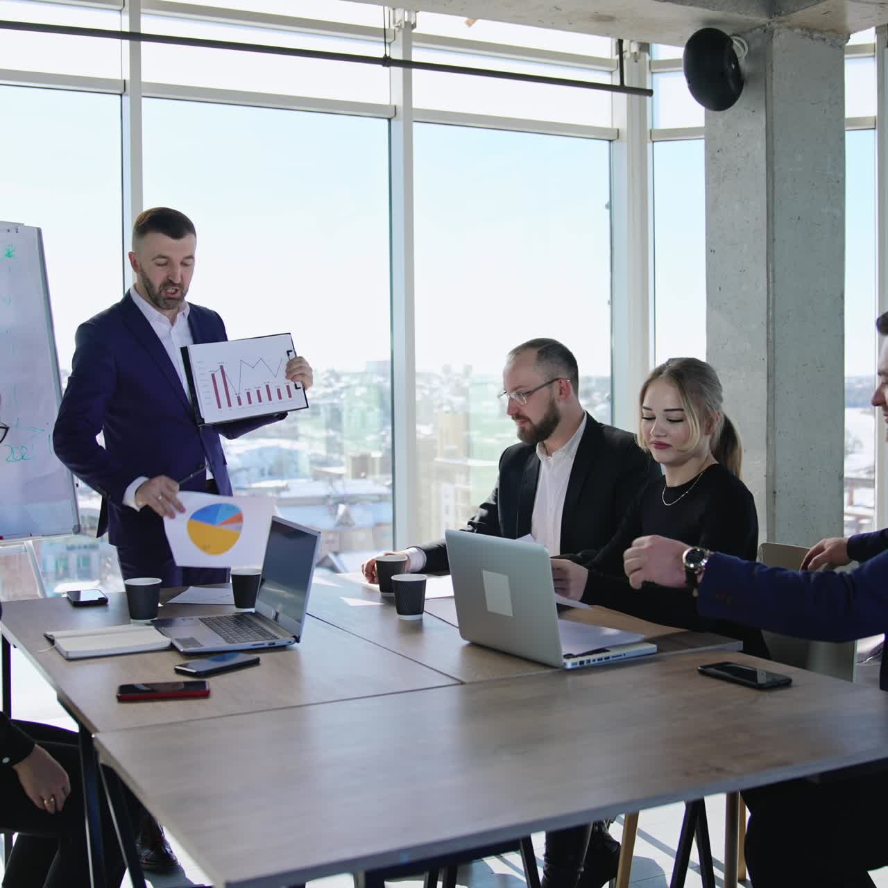 Communication and discussion at the business meeting. Cooperative team discussing charts at the table in the office. Cityscape at the backdrop