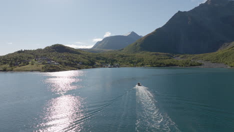 Tourboat-on-cruiser-boat-in-Norwegian-Lyngen-fjord-with-Scandinavian-Alps-in-background-on-sunny-summer-day,-Norway
