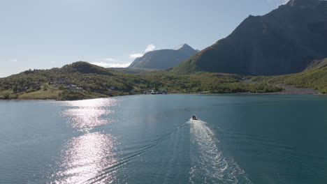 tourboat on cruiser boat in norwegian lyngen fjord with scandinavian alps in background on sunny summer day, norway