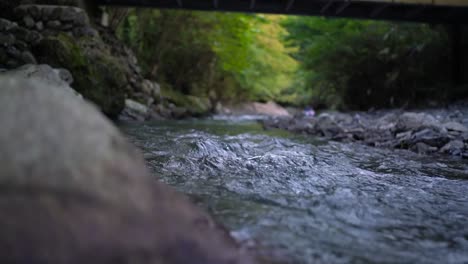 low angle nature shot of rock, reveal stream of water flowing. slow motion rack focus shot