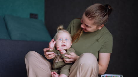 mother sits with her lovely infant baby. woman plays clapping hands game with her adorable son.