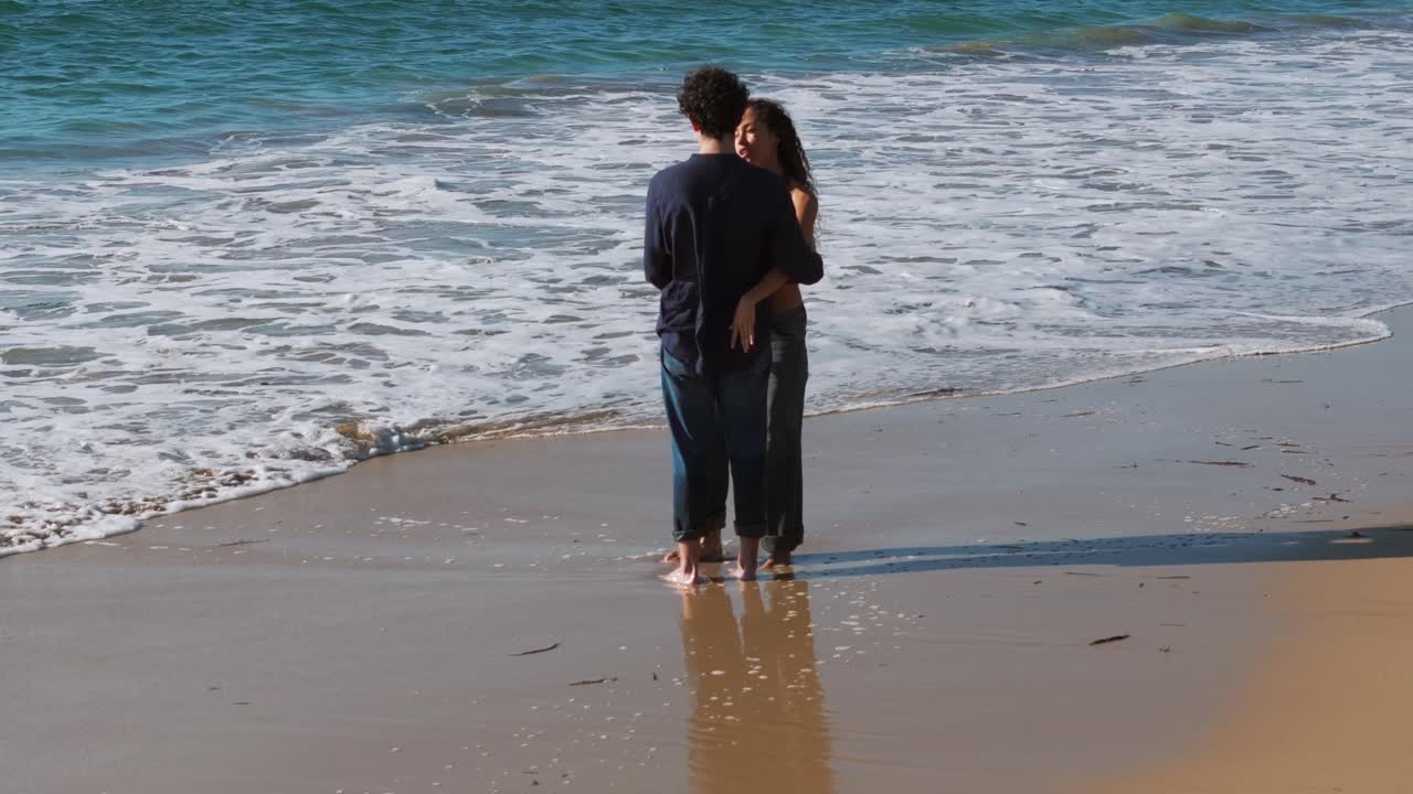 Young In-Love Couple On The Beach With Crashing Waves In Praia do Lago, Muxia, A Coruna, Spain. Rotating Shot