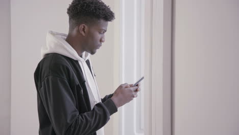 Profile-of-serious-young-man-using-mobile-phone-indoors