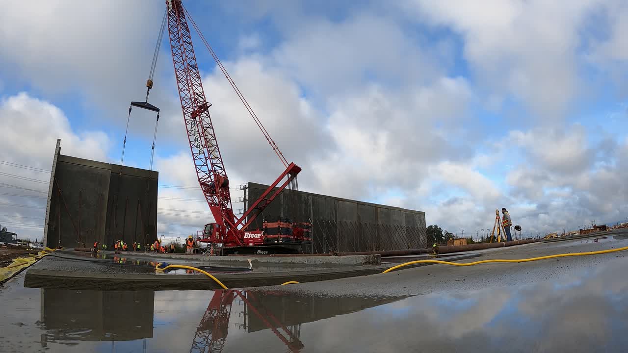 Concrete wall being lifted into place by a crane for commercial warehouse