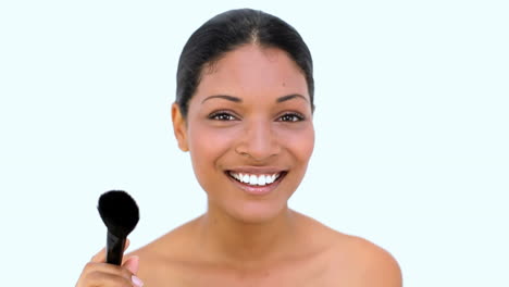 una mujer hermosa usando un pincel para su cara.