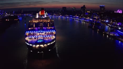 queen mary 2 cruise ship in hamburg harbour at cruise days in the night during blue light show across the city of hamburg