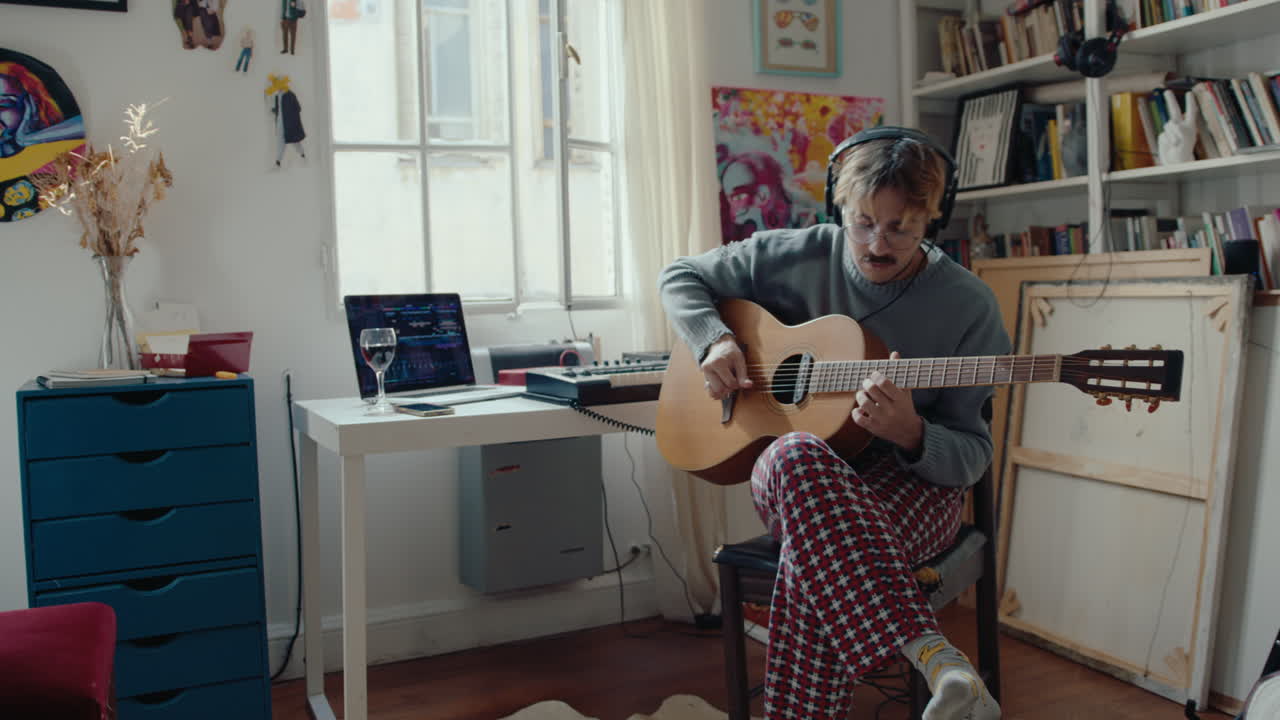 Musician in Headphones Playing the Guitar at Home Studio