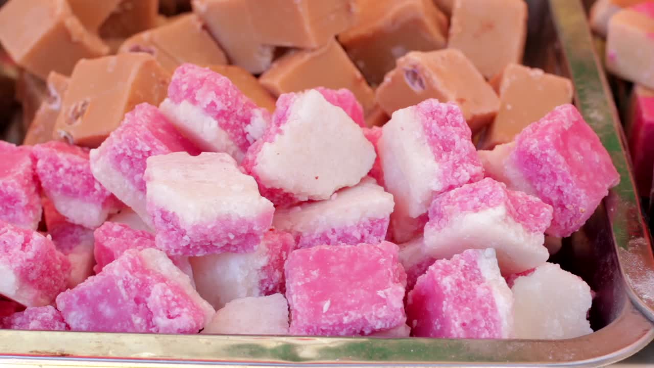 Pink and white coconut ice sweets on a street food market stall.