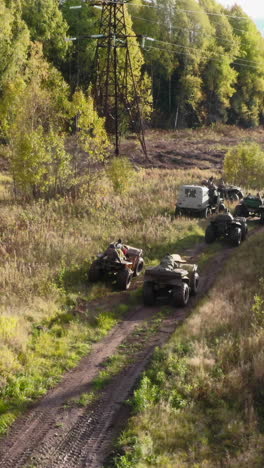 people driving atvs on a dirt road through a forest