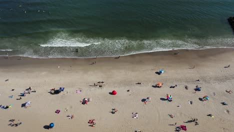 Una-Vista-De-Pájaro-Sobre-La-Gente-Que-Se-Relaja-En-La-Playa-En-Un-Día-Soleado