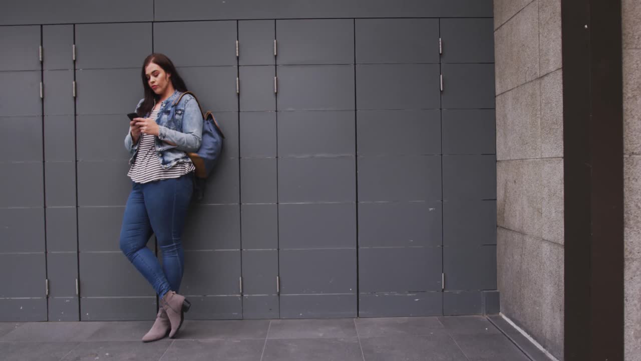 Giovane donna caucasica in piedi che tiene in mano il telefono