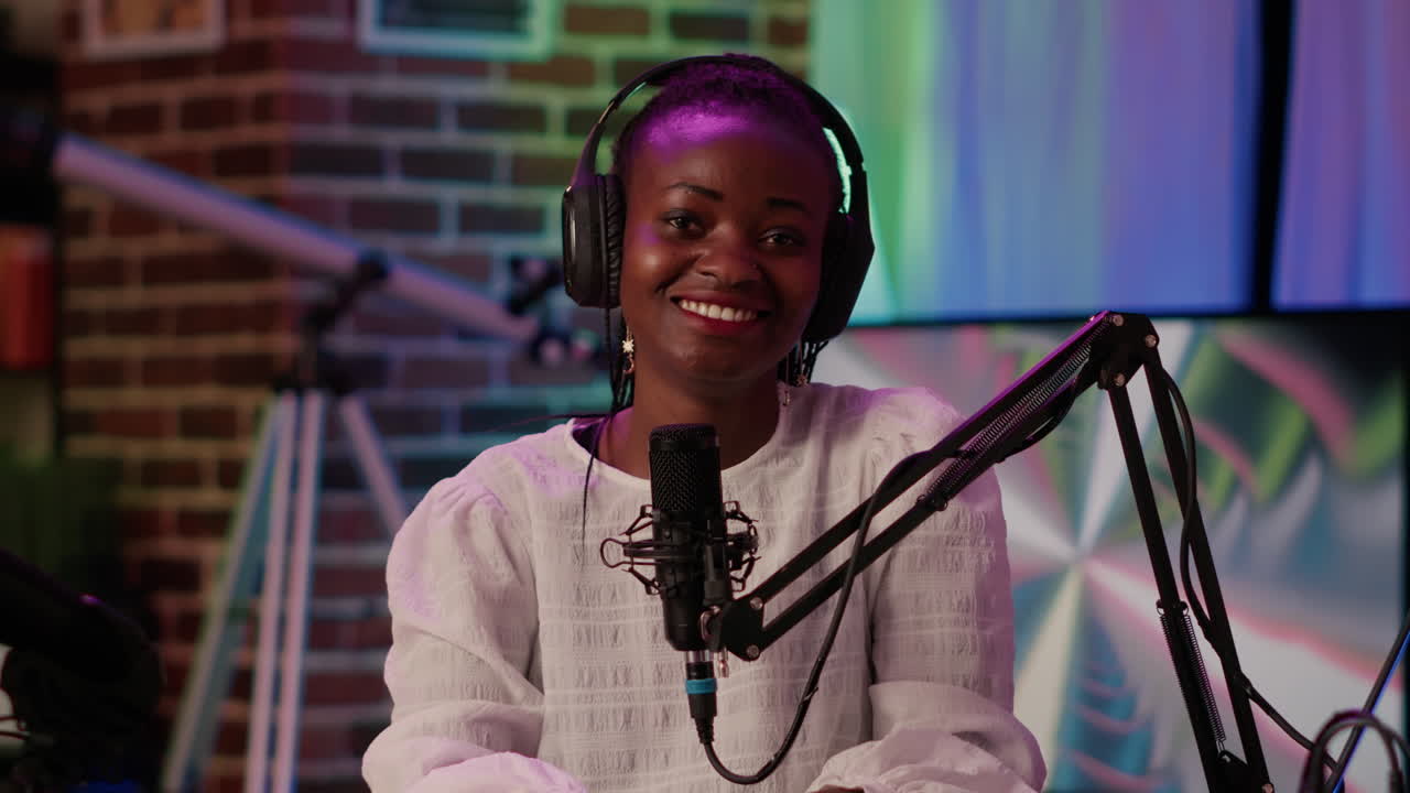 Portrait of african american woman podcaster sitting at desk reading content from laptop screen