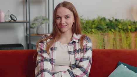 portrait of happy one beautiful teenager student girl smiling, looking at camera at home on sofa