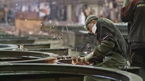 worker polishing steel part at metal fabrication facility