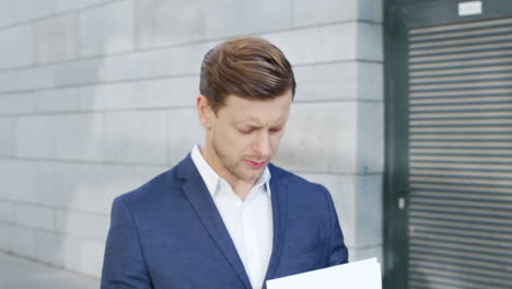 Businessman-reading-papers-on-street.-Male-entrepreneur-working-with-documents