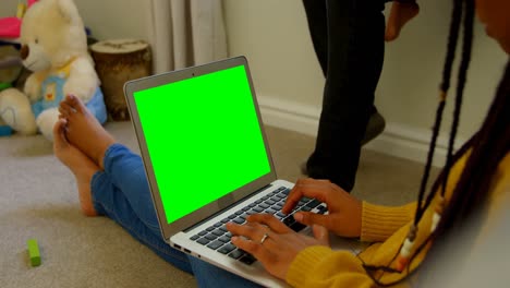 Side-view-of-young-black-woman-using-laptop-and-sitting-on-floor-of-comfortable-home-4k