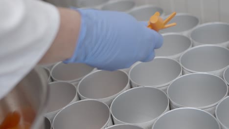 el trabajador pone cucharas pequeñas en diferentes latas en una fábrica moderna y limpia