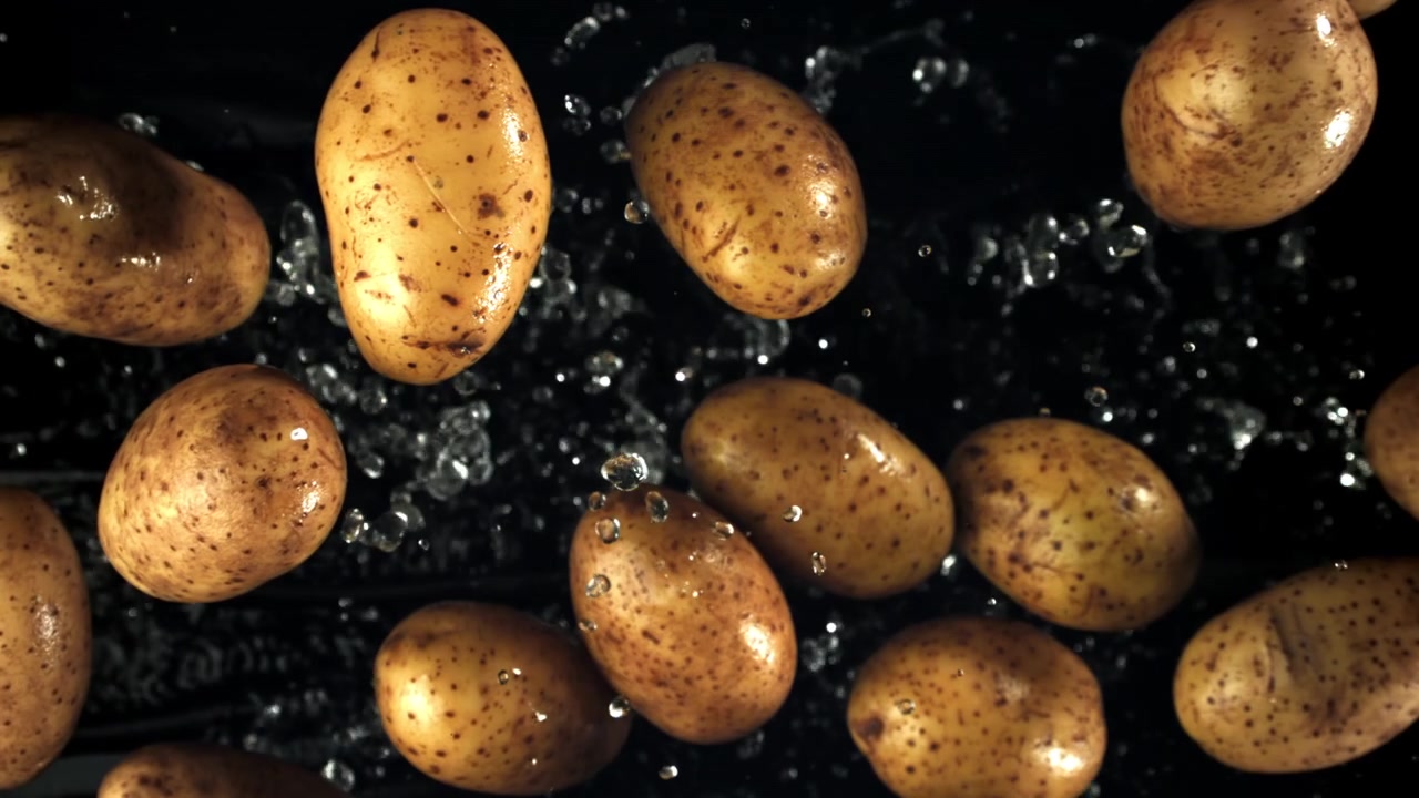 Patate fresche che cadono e creano schizzi d'acqua su sfondo nero