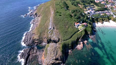 aerial footage of cliff in coastal village waves crashing and jade water