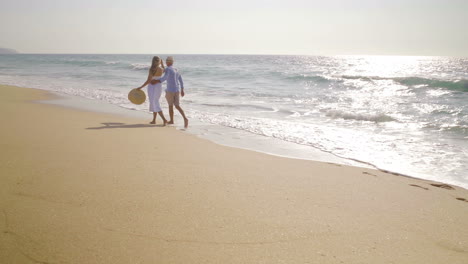 vista de atrás de una pareja caminando juntos en la playa