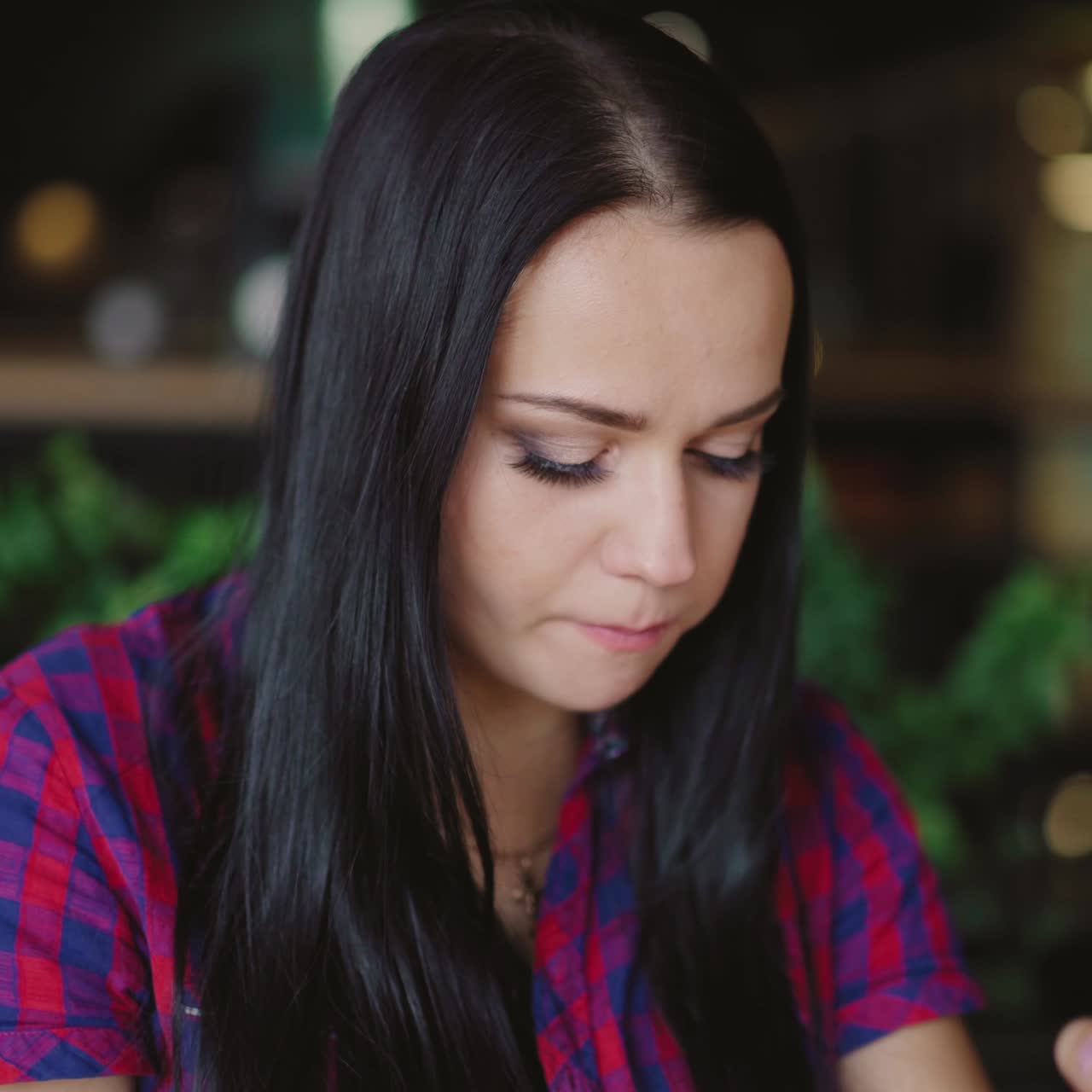 beautiful woman in a plaid shirt is drinking juice in the cafe on the background of the interior