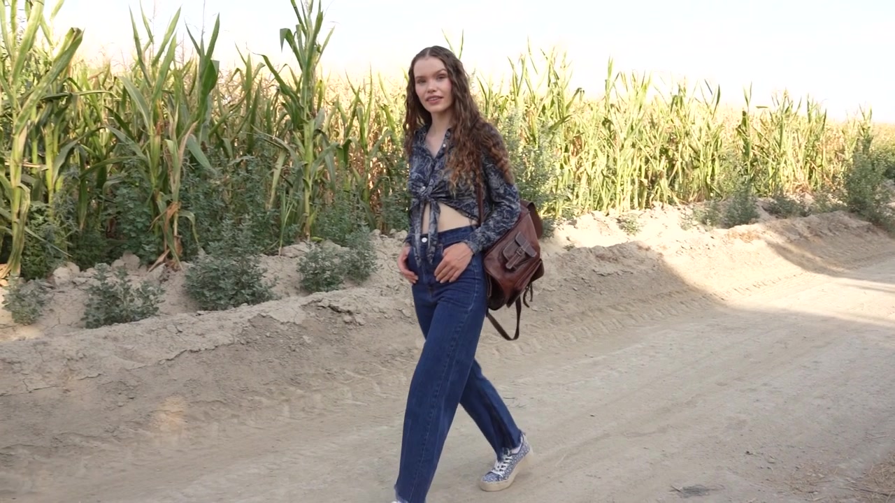 Una giovane donna passeggia tranquillamente lungo una strada polverosa completamente circondata da una natura meravigliosa.