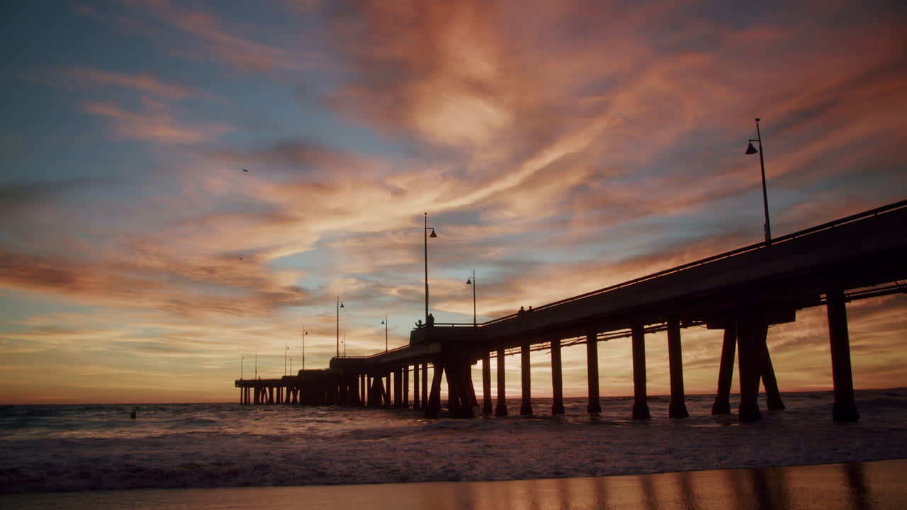 Silhouette of a pier at sunset with colorful clouds