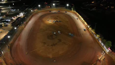 slight aerial orbit of oval dirt track racing during a race at night