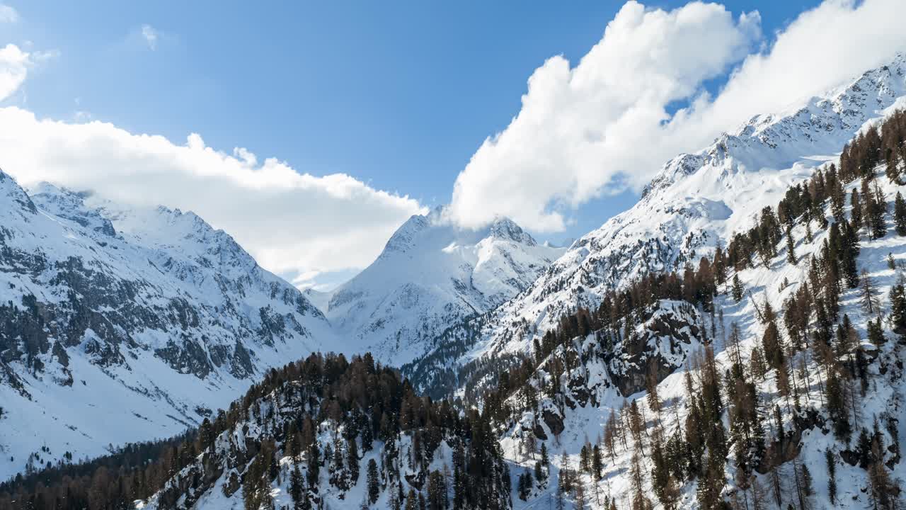 Montagne innevate e alberi alpini sotto un cielo azzurro e limpido nel Passo del Maloja, Svizzera. Hyperlapse aereo, con avanzamento.