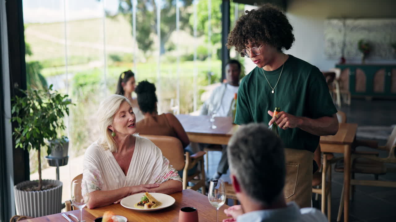 Waiter Pouring Wine for a Senior Couple in a Restaurant