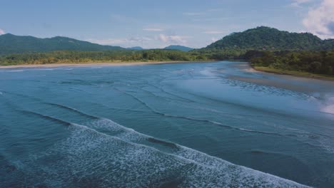 4k aerial drone footage of a perfect empty beach with long waves rolling on the shore at the pacific ocean in costa rica on a nice sunny day