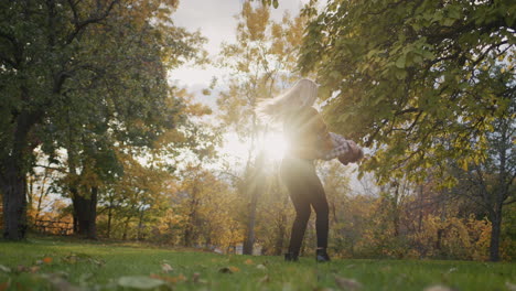 A-happy-young-mother-circles-her-child,-has-a-good-time-together-on-a-walk.-Against-the-backdrop-of-sunset