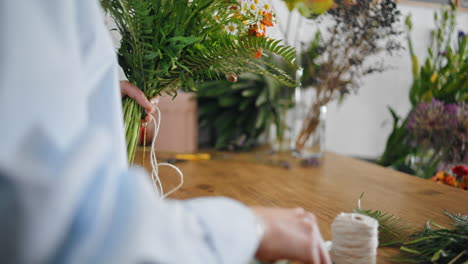las manos de los floristas de primer plano hacen decoración de flores de ramo en la tienda de plantas entrega de venta
