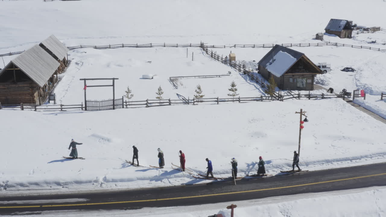 Tuva men dressed in traditional clothing walking in fur ski in snow, Hemu Village, Xinjiang, China. Epic aerial view
