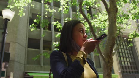 African-american-woman-wearing-face-mask-talking-on-smartphone