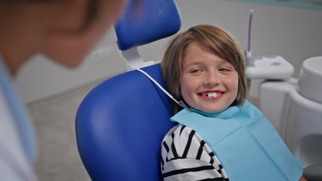 Kid sitting dentist appointment in modern clinic closeup. Happy boy smiling