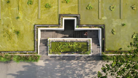 woman walking down staircase entrance to maua hotel and resort in nusa penida, bali indonesia, aerial top down