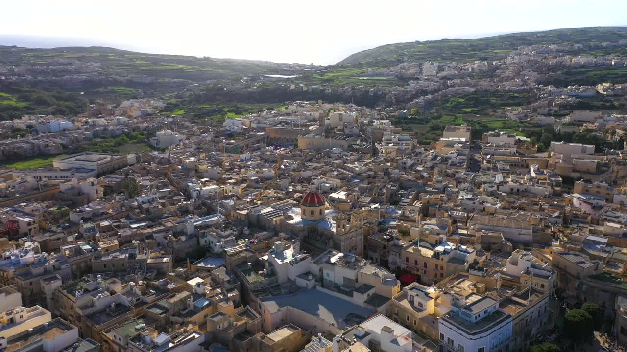 el video muestra el casco antiguo de gozo donde la iglesia está rodeada de casas antiguas.