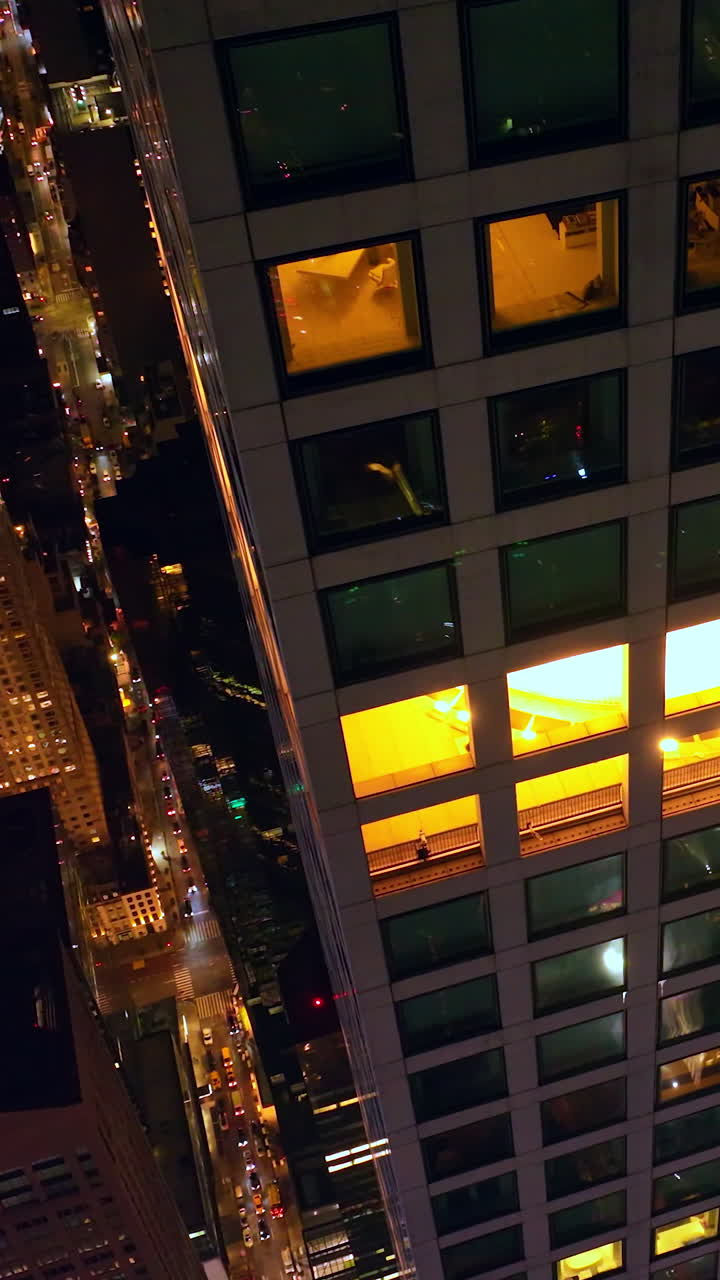 Flying high around the skyscraper at night. Stunning scenery of amazing New York with billions of lights. Top view. Vertical video